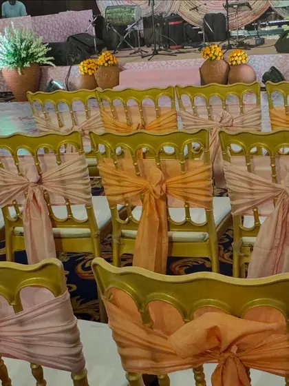 Guest seating for the Bhaat ceremony. The chairs are decorated with peach and orange organza ties, adding a soft and festive touch to the event hall.