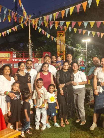 A beautiful evening celebration at Tingaland Xtreme. This photo shows a large family group enjoying an outdoor birthday party under festive carnival lights.