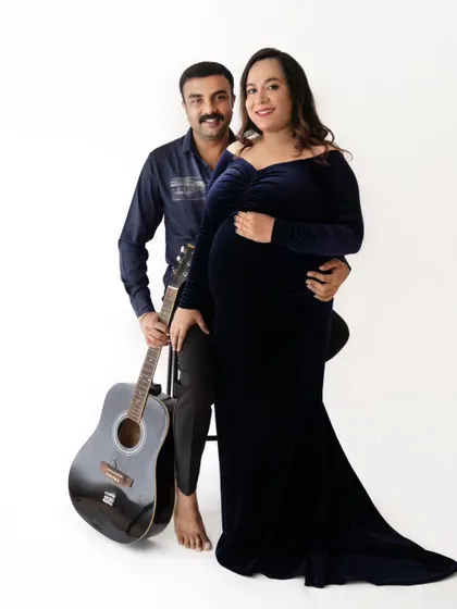 A creative couple's portrait where the partner holds a guitar, adding a personal and musical touch to their maternity session.