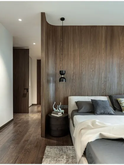 The rich texture of the wood partition serves as a warm, natural headboard. The minimalist pendant light adds a touch of modern design without cluttering the space.