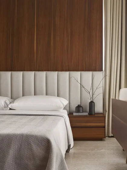 A detail of the master bedroom's custom headboard and walnut wall paneling. The combination of the plush, channel-tufted headboard and the rich wood grain creates a backdrop that is both comforting and sophisticated.