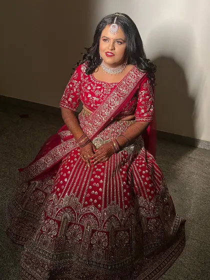 A full-length view of the bride in her magnificent red lehenga. The heavy embroidery of her outfit is balanced with classic makeup and hair, making her look truly regal.