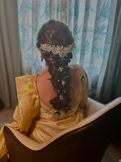 A view of the intricate bridal braid, beautifully woven with baby's breath. This hairstyle adds a touch of modern romance to the traditional South Indian look.