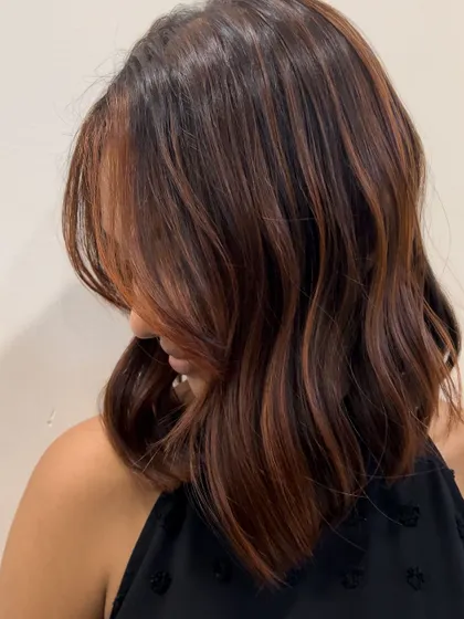 Another angle of this beautiful reddish-brown balayage on a shoulder-length cut. The placement of the color is designed to frame the face and add warmth.