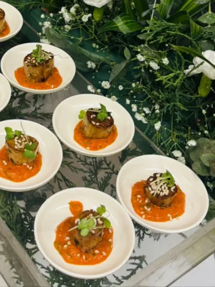An artfully presented appetizer featuring a savory base with a rich topping, garnished with microgreens. This bite is served on an individual white dish, showcasing our attention to detail in plating and presentation.