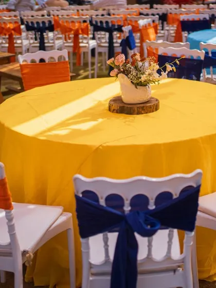 Colorful table settings for the Mexican fiesta. Bright yellow tablecloths are paired with blue and orange chair ties, creating a vibrant and festive dining area.