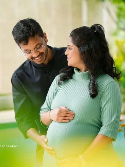 A sweet, candid shot of a couple sharing a smile by a poolside, framed by lush greenery. These natural interactions make for the most cherished maternity photos.