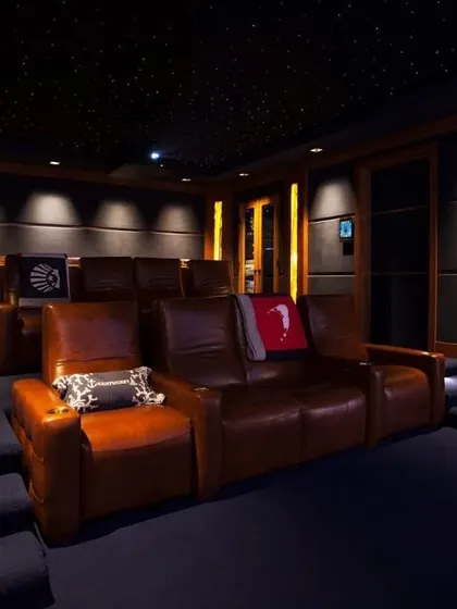 A cozy and luxurious home theater with tiered brown leather sofas. This setup is perfect for creating an intimate yet premium viewing experience, complete with a starlight ceiling and professional acoustic wall panels.
