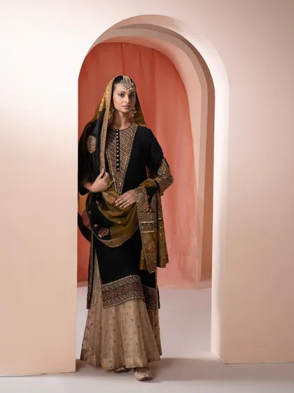 The full view of the black and gold suit, styled as a sharara. The regal headpiece and earrings elevate it for a more formal event.
