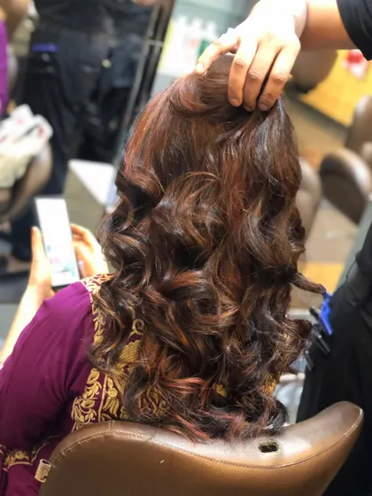 Rich copper and auburn tones woven into dark hair. The curls help to showcase the multi-tonal effect of this colour service.