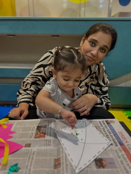 A mother and daughter enjoy a quiet moment of crafting together, decorating a paper kite.