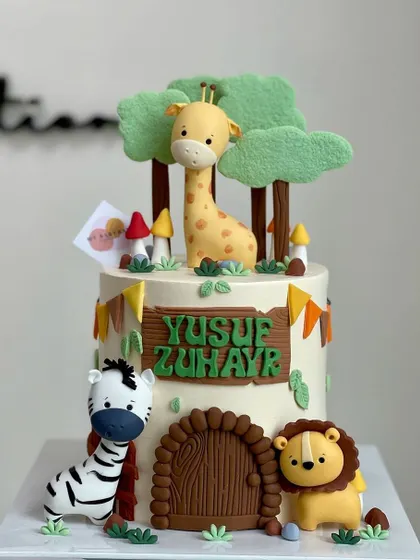 This adorable jungle cake features a whole crew of cute fondant animals, including a lion, zebra, and giraffe, peeking out from behind trees and a wooden door.