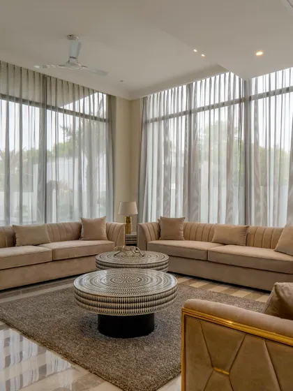The drawing room of the farmhouse project, designed for comfort and style. The space is arranged for conversation, with large windows providing ample natural light and views of the garden.