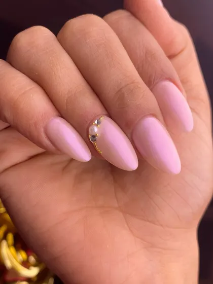 A simple and elegant light pink manicure on almond nails, elevated with a beautiful crescent of tiny pearls and crystals at the cuticle for a touch of "caviar" luxury.