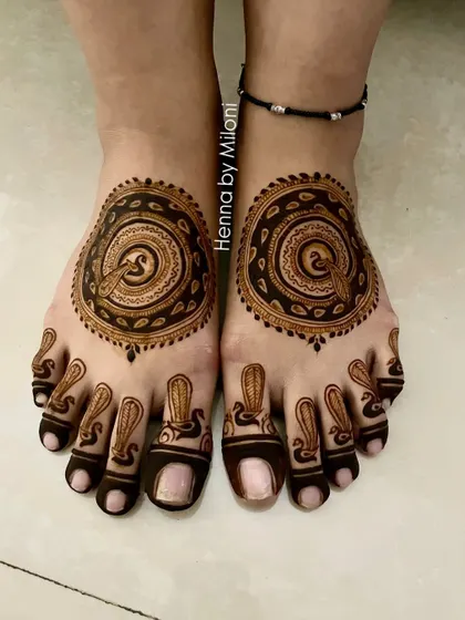 A variation of the peacock-themed circular foot mehendi. The dark, bold lines create a striking and beautiful design.