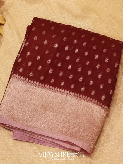 A rich maroon Kora silk saree with similar floral motifs and a wide silver zari border.