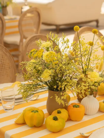 The tablescape details included fresh yellow peppers and lemons alongside delicate yellow flowers, adding a unique and organic touch to the decor.