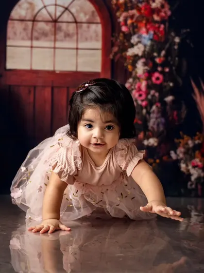 Crawling into her first birthday celebration. The floral archway and rustic door create a magical entrance for this little one's special day.