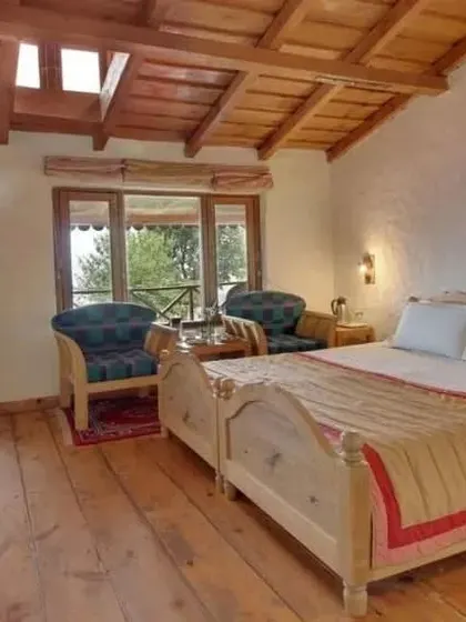 A duplex room interior at the Eco Lodge, featuring natural wood floors, a simple and clean design, and a balcony with a view.