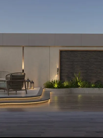 The same terrace view at dusk, where the integrated LED lighting along the curved steps and planters transforms the space. This thoughtful landscape lighting design creates a warm, inviting, and functional outdoor room for evening relaxation.
