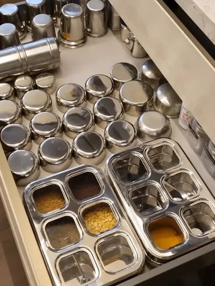 A well-organized spice drawer with traditional Indian steel "dabbas" and masala boxes. This setup keeps all spices handy for cooking.