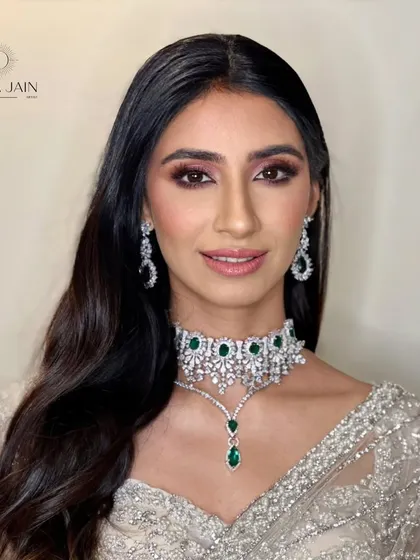 A portrait of the client, where her soft, open hairstyle highlights her stunning emerald and diamond choker.