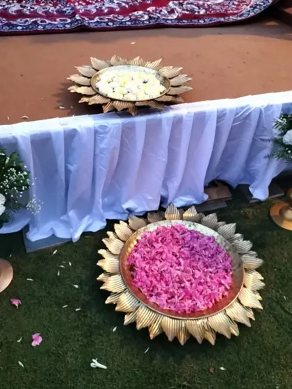 Traditional 'urli' bowls made of brass, filled with pink and white flower petals, are a beautiful and customary decor element for Indian weddings.