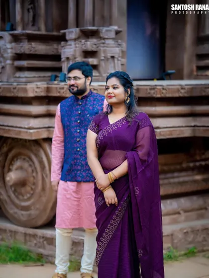 A regal and stylish portrait of a couple posing against a stone chariot structure.