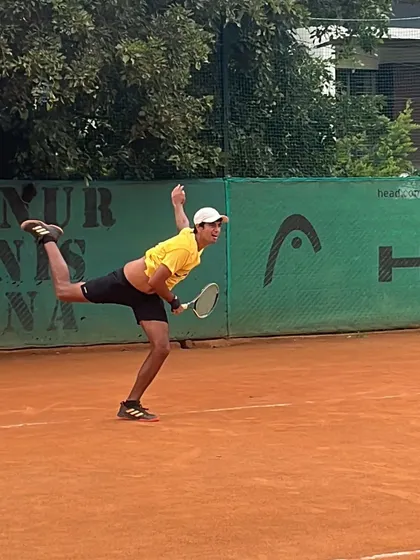 This image captures the peak of a kick serve motion, showing the body rotation and flexibility required for this advanced technique.