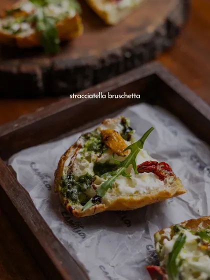 A close-up of my Stracciatella Bruschetta, showcasing the creamy cheese, vibrant pesto, and sweet sun-dried tomatoes on a perfectly toasted slice of bread.