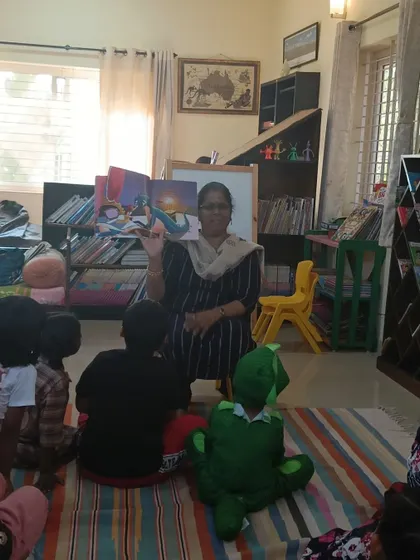 The storyteller proudly displays the book's cover, introducing the characters to the children.