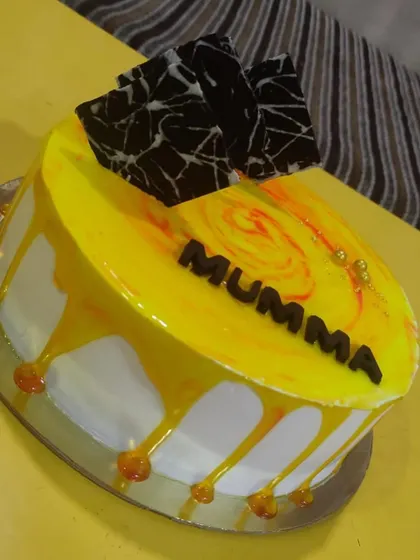 A bright and cheerful butterscotch drip cake for "Mumma". The vibrant yellow glaze and abstract chocolate shards make this a sunny and delicious choice for a special occasion.
