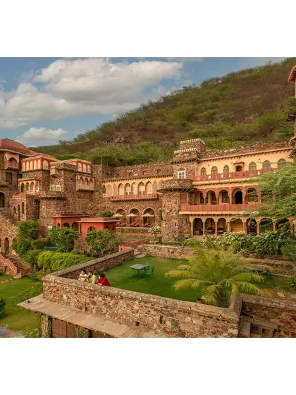 This photograph captures the multi-level architecture and verdant courtyards of the Neemrana property, showing the intricate relationship between the structure and its natural surroundings.