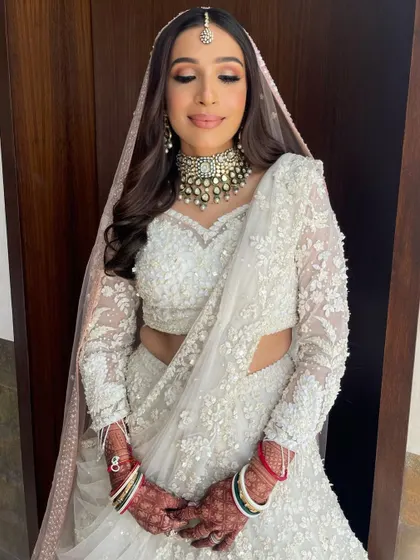 A beautiful bride in a stunning white lehenga. I styled her hair with soft waves and a center part to complement her maang tikka.