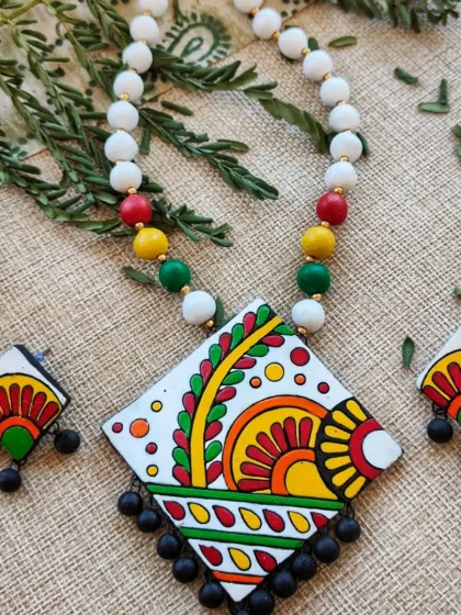 The same diamond-shaped pendant necklace, with a clean white background that makes the colorful motifs pop.