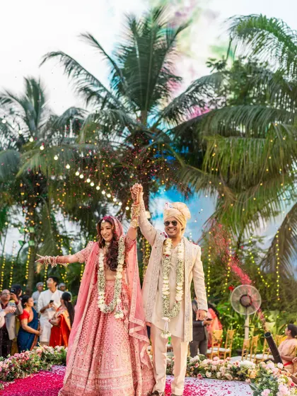 A beautiful shot of the couple, hands raised in joy, after successfully completing the varmala ceremony.