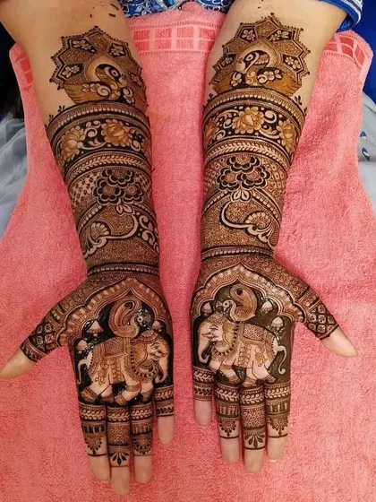 A stunning example of symmetrical bridal mehandi. Both hands feature majestic elephants on the palms and peacocks on the wrists, creating a balanced and regal design that is rich in traditional symbolism.