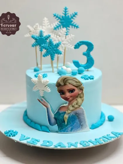 A magical Frozen-themed cake for a 3rd birthday. The cool blue frosting is adorned with edible snowflakes and an image of Elsa, creating a winter wonderland for any Frozen fan.