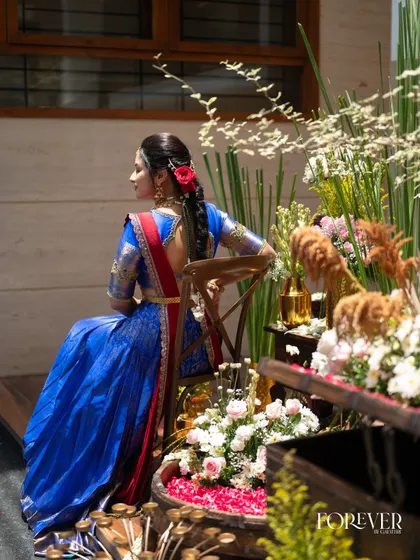 A candid moment showing the complete traditional look, including a beautiful braided hairstyle with fresh red flowers, perfect for a bangle ceremony.
