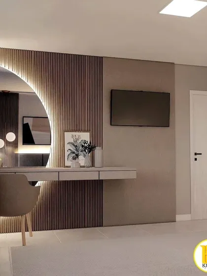 A view of the TV and dressing table area, showing the fluted wood panel and the large, backlit mirror.