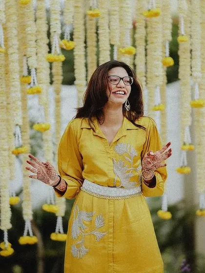 A guest laughing in front of a beautiful marigold curtain, a perfect candid moment from the Haldi.