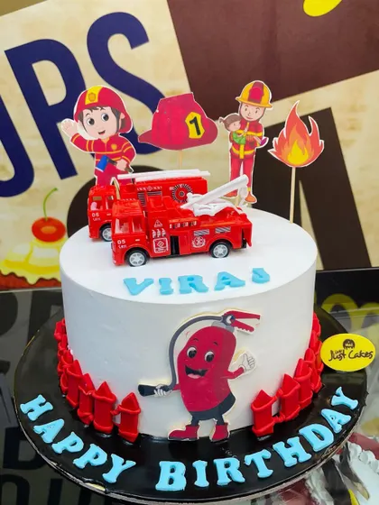 A 2.5kg firefighter theme cake with a toy fire truck, flames, and a fire extinguisher character.
