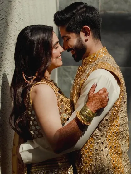 A tender moment between the couple at their Mehndi function, their mirror-work outfits shimmering in the sunlight.