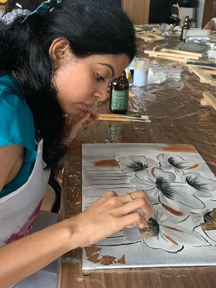 A participant carefully applying gold leaf to her floral painting. It's a delicate process that yields stunning results.
