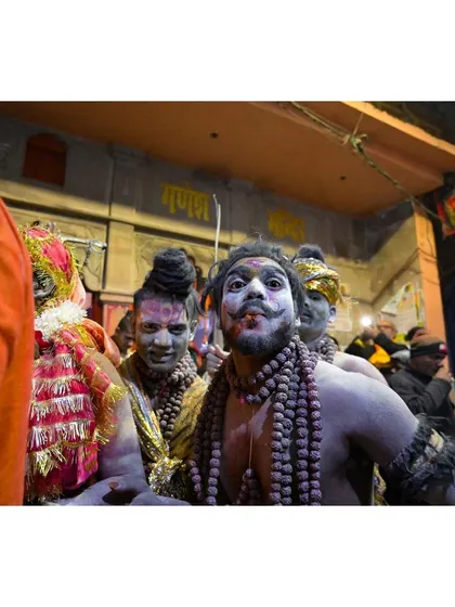 A devotee, his face painted for a festival, looks directly at the camera from within the crowd. This candid portrait captures a moment of direct engagement and personal expression amidst the larger celebration.