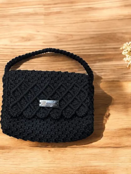 A classic black handbag with a scalloped flap. This is a timeless piece for any wardrobe.