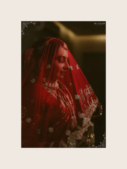 A moody and artistic portrait of the bride, her red veil creating a soft filter. This frame captures the quiet moments of reflection during her beautiful inter-cultural wedding day.