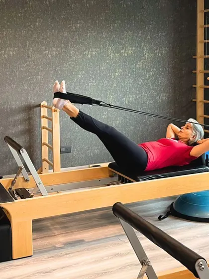 Stretching in style. A client works on her hamstring flexibility and core control on the Reformer.