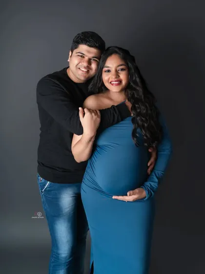 A beautiful bodycon gown in a striking blue. This classic studio portrait focuses on the couple's happy smiles and the beautiful shape of the baby bump.