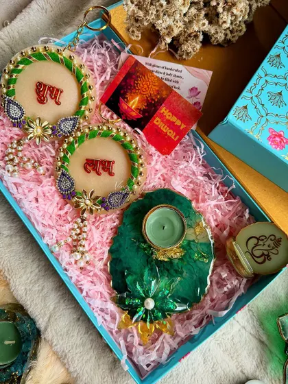 A green-themed Diwali hamper with "Shubh Labh" hangings, a geode-style diya, and a Ganesha container.